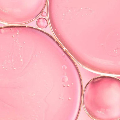 Natura Bissé Hydrating Revitalizing Essence with a smooth pink liquid texture in droplets