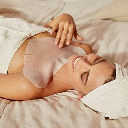 Natura Bissé Neck Mask applied on a smiling woman relaxing on a bed with a towel on her head