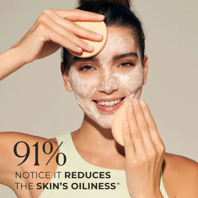 Woman applying Natura Bissé Purifying and Deep Cleansing Mask to her face with a cleansing sponge