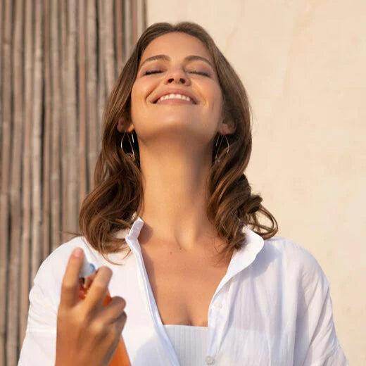 Woman using Natura Bisse Revitalizing Citrus Spray for refreshing hydration and a revitalized glow