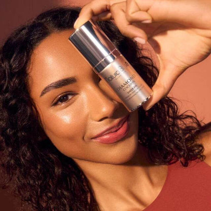 Natura Bisse Tinted Eye Cream in a sleek bottle held by a woman showcasing her radiant skin