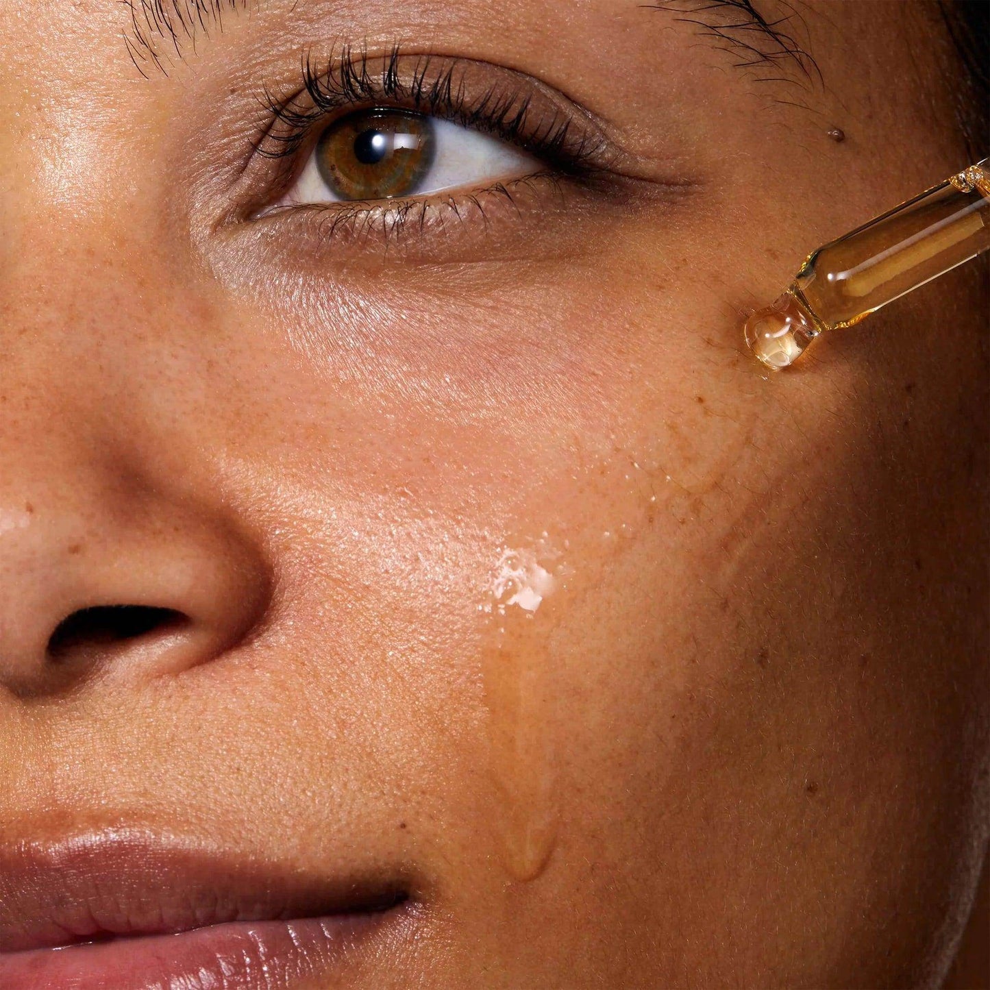 Close-up of a woman applying Omorovicza Bakuchiol Facial Oil for radiant skin