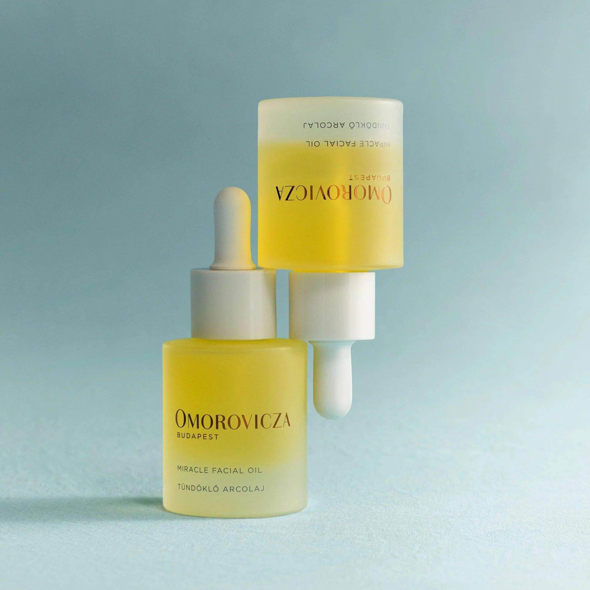 Omorovicza Bakuchiol Facial Oil in glass dropper bottles with a soft blue background