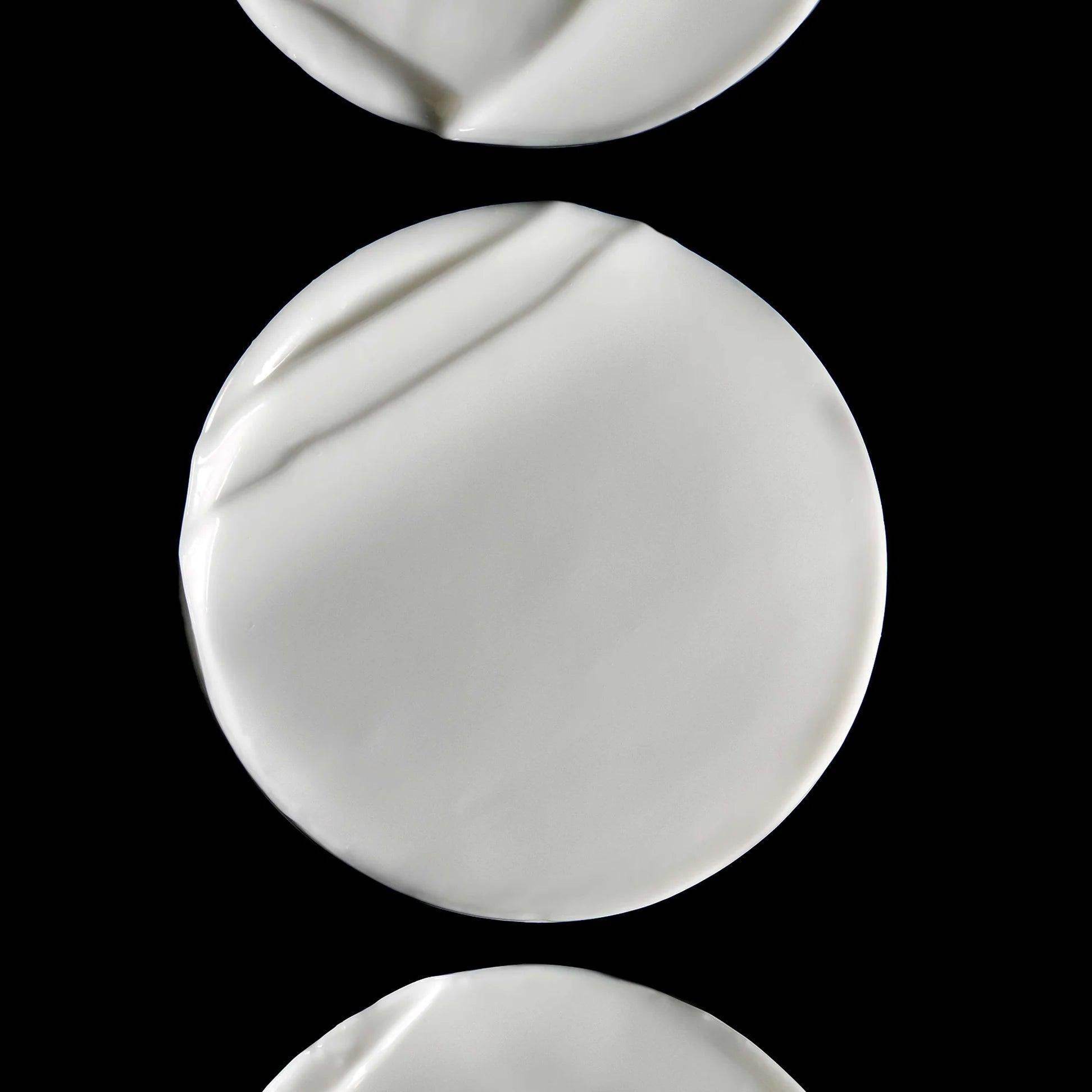 Omorovicza Body Cream displayed in a smooth, white texture atop a black background