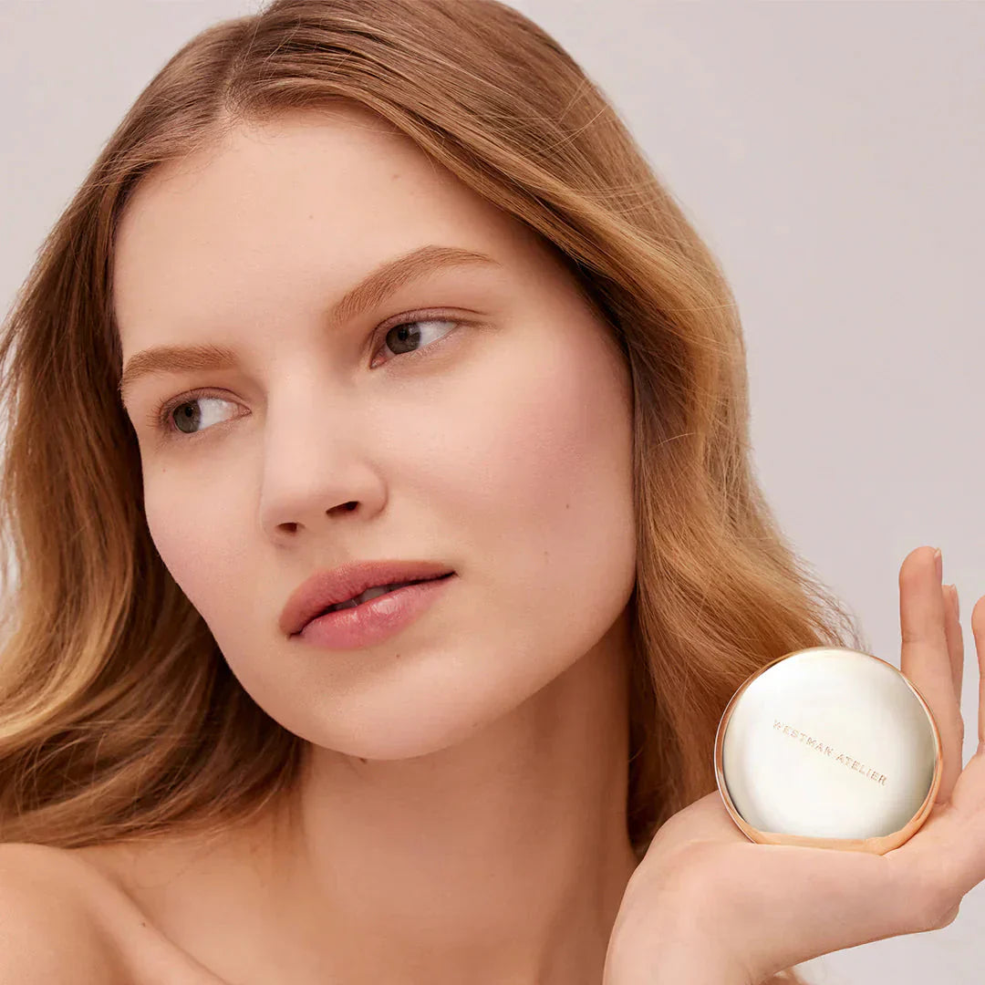 Westman Atelier Pressed Powder compact held by a model for a flawless complexion