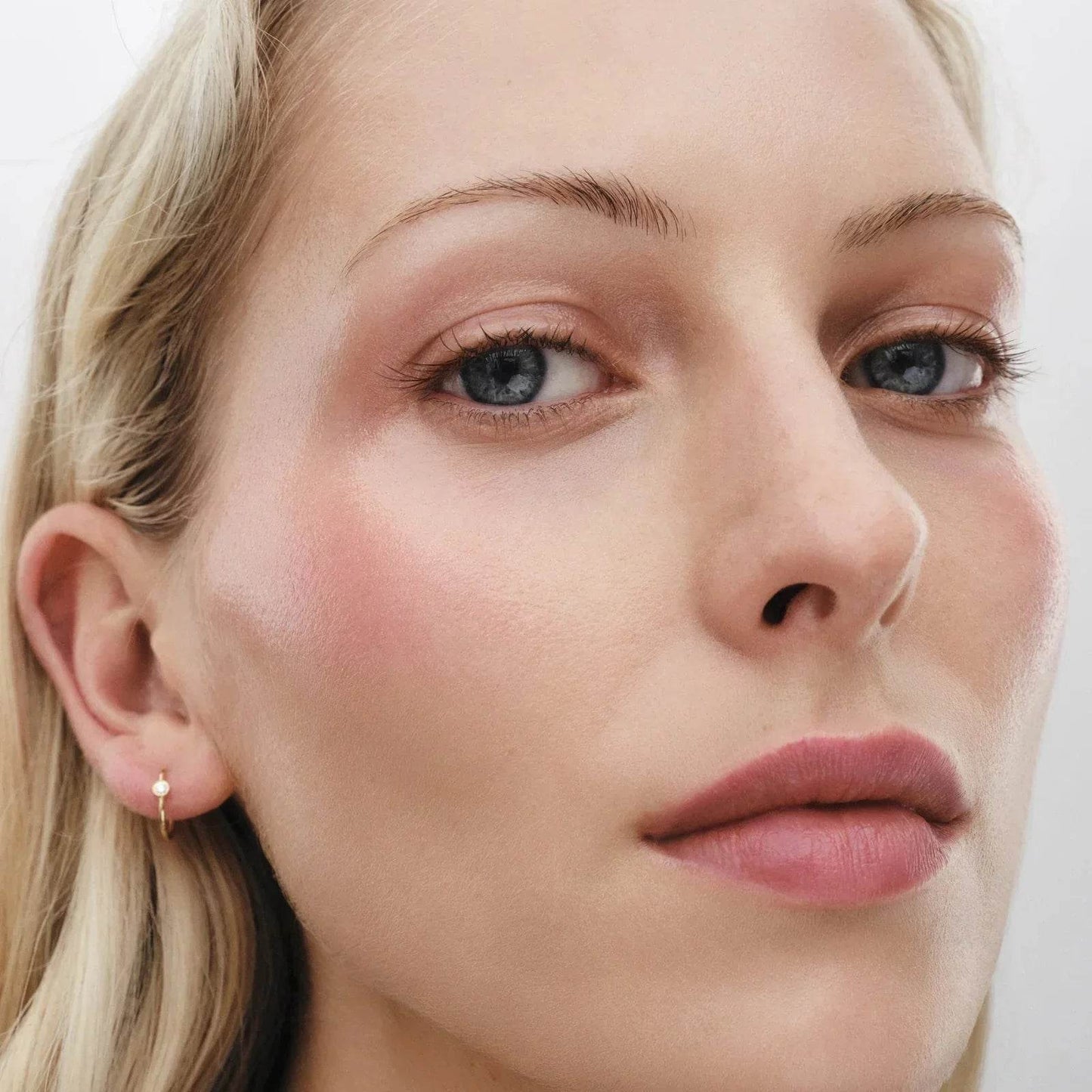 Westman Atelier Highlight Stick on model with glowing skin and natural makeup look